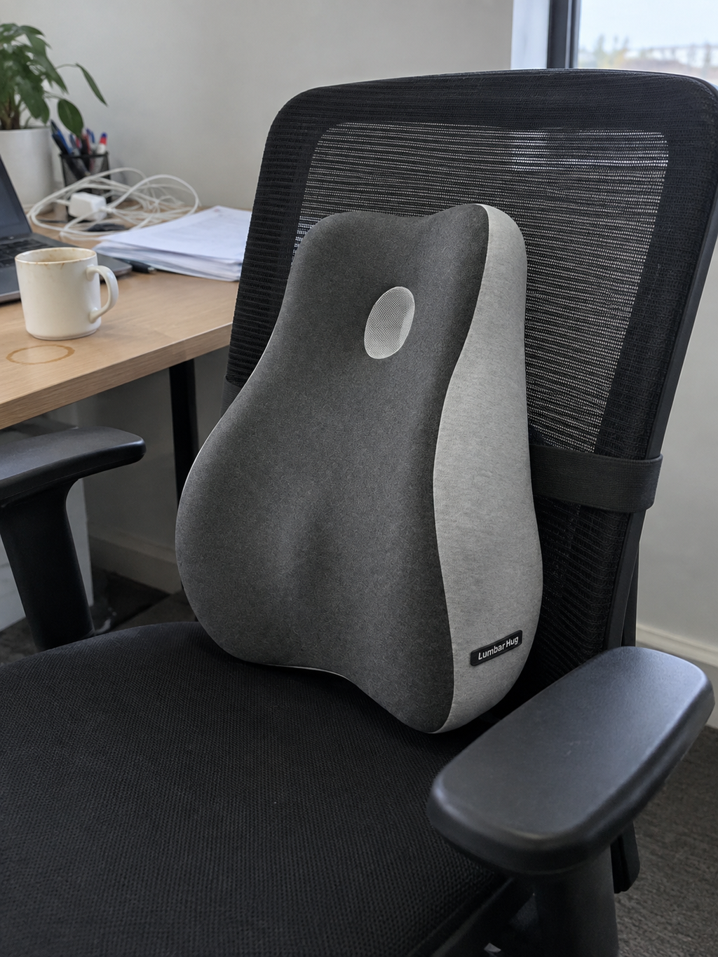 OrthoCore lumbar support pillow strapped to a black mesh office chair at a home office desk