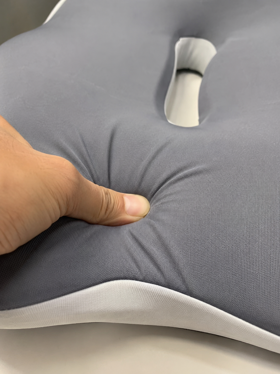 Hand pressing into the OrthoCore seat cushion showing the memory foam compress